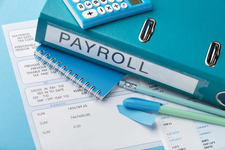 Payroll documents and calculator arranged on a desk, representing business payroll processing with Uma Tax.